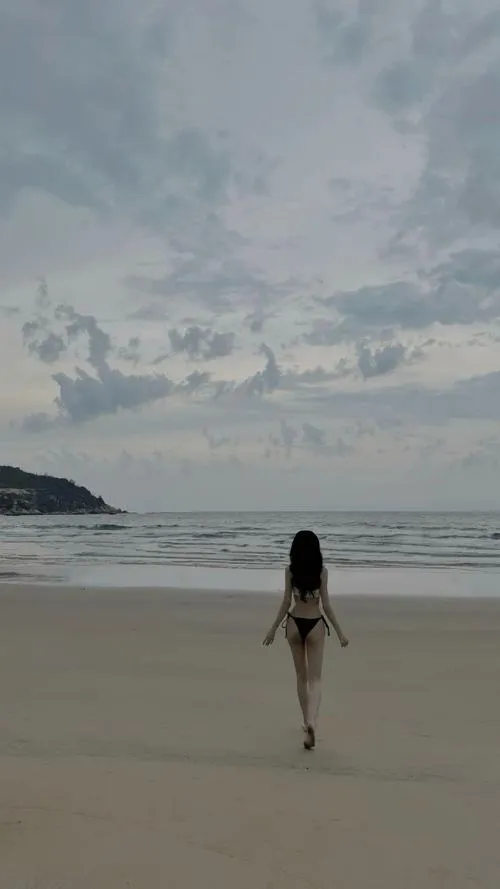 Cô gái xinh lặng lẽ bước trên cát trắng che mặt quay lưng khoe đùi thon và lưng cong mềm