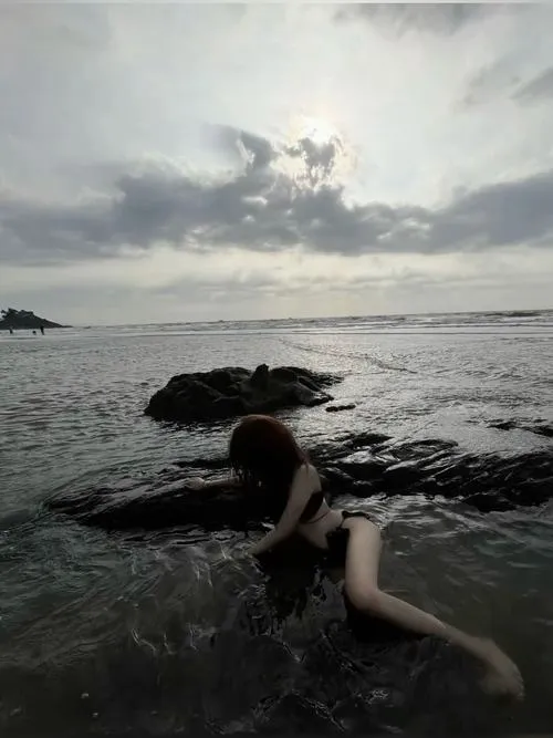 Cô nàng che mặt bằng tóc nằm trên đá ướt da rám nắng quyến rũ mắt nhìn xa xa