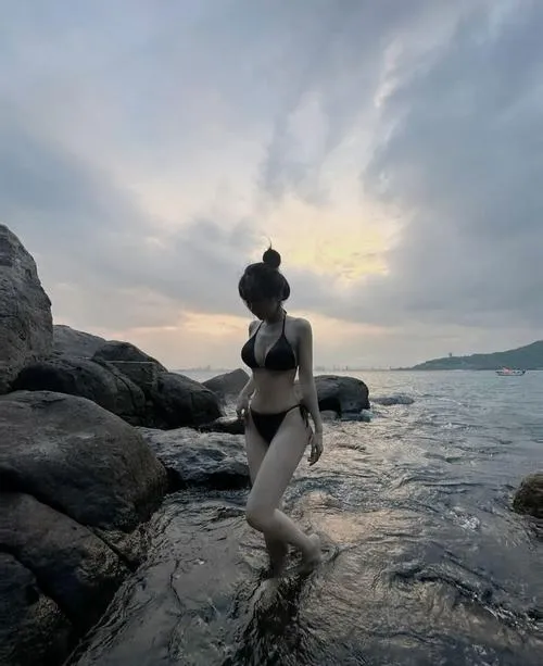 Ảnh chụp du lịch biển với đồ bơi che mặt ngồi trên đá ngược sáng khoe vai thon và eo