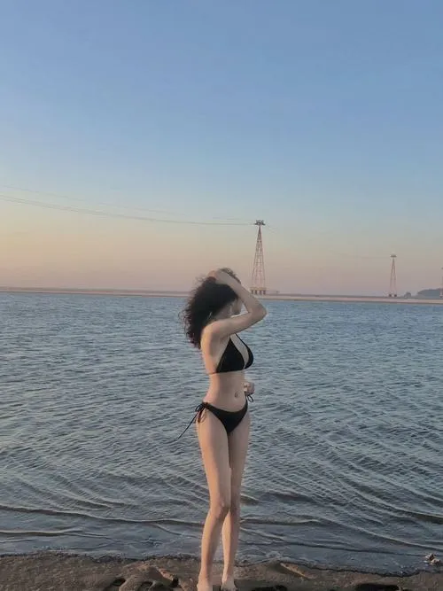 Bikini che mặt ngoài biển lúc hoàng hôn dáng đứng nghiêng làm ngực đầy nổi bật trên nền trời