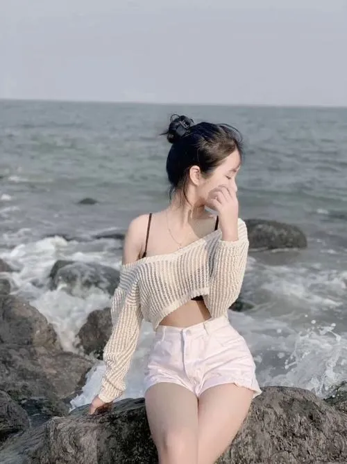 Nàng mặc áo khoác lưới che mặt nhìn sang bên tóc búi hờ khoe cổ và bờ vai trắng