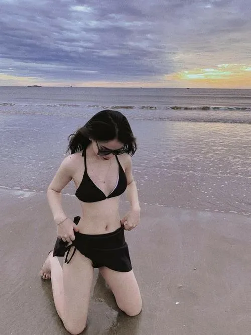 Cô gái mặc bikini che mặt cúi nhẹ nhìn cát vòng một căng vừa đủ tóc xõa che kín