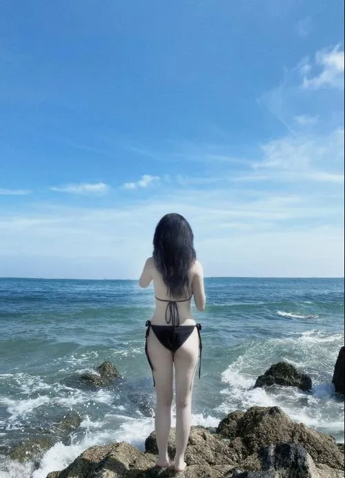 Gái xinh bikini quay lưng bên bờ kè tóc dài che gáy đôi chân thon đứng vững giữa gió