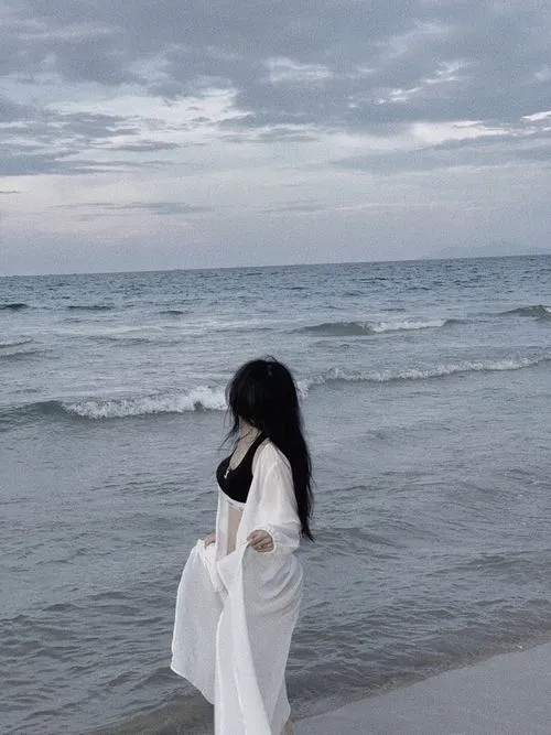 Ảnh nàng thơ ngoài biển mặc váy quấn hông che mặt bước chậm trên cát dáng dịu mà gợi