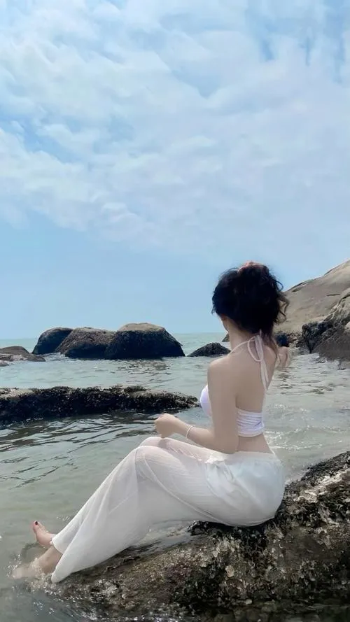 Cô gái che mặt ngồi trên đá nhìn biển xa tóc rũ lưng vòng một nổi nhẹ rất hút