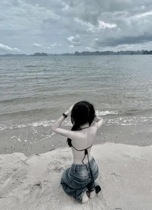 Ảnh gái xinh đi biển bikini che mặt quay lưng sát bờ nước váy mỏng bay làm dáng mơ