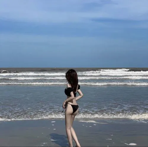 Cô nàng mặc bikini che mặt tạo dáng trước sóng tóc bay rối nhẹ làm lộ bờ vai mịn màng