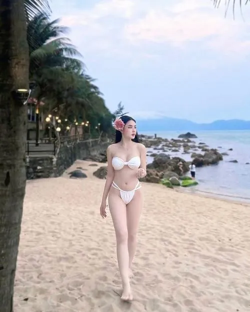 22 Nàng bikini trắng bước trên cát, tóc dài, ánh nhìn xa, biển xanh cát trắng.