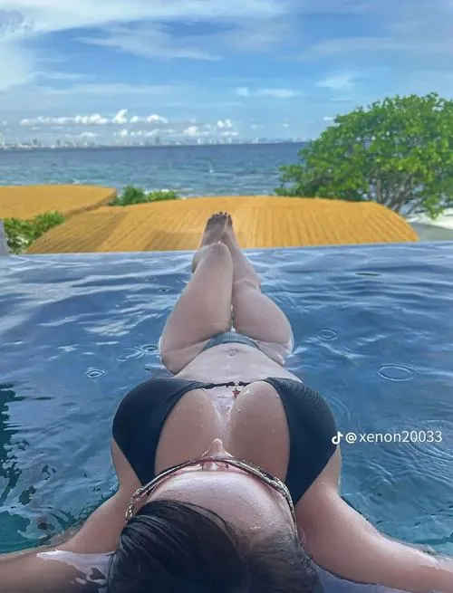 30 Nàng nằm sấp trên phao, bikini tối màu, lưng cong, nước xanh mát rượi.