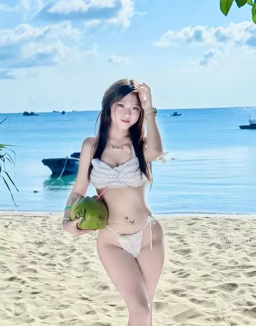 34 Nàng bikini trắng trên bãi cát, tóc dài, nụ cười tươi, da sáng tự nhiên.