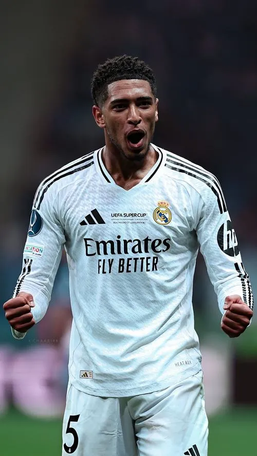 30 Hình đẹp Jude đứng cạnh cúp, nền vàng kim huy hiệu, ánh sáng ấm làm khung hình sang hơn hẳn.