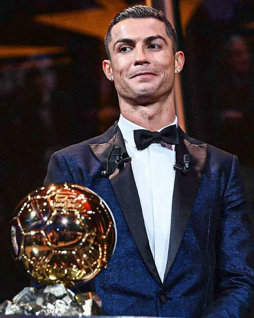 11 Khung hình vest xanh đậm, ôm quả bóng vàng trước ngực, ánh sáng làm nổi gương mặt.