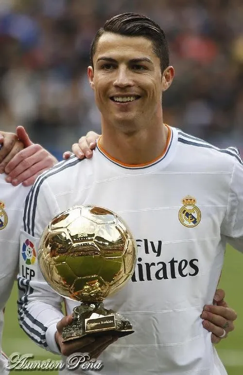 13 Ảnh áo Real Madrid cầm quả bóng vàng và vẫy tay, hậu cảnh sân vận động mờ nhẹ.