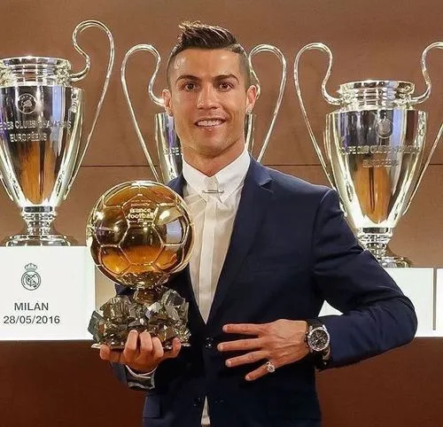 17 Trước dãy cúp lớn, ôm quả bóng vàng, bố cục trung tâm tạo cảm giác quyền lực, vững chãi.