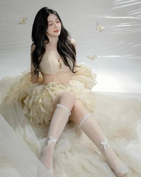 39 Cô ngồi tựa mép hồ, bikini đen, ánh phản quang tạo cảm giác mát và sang.