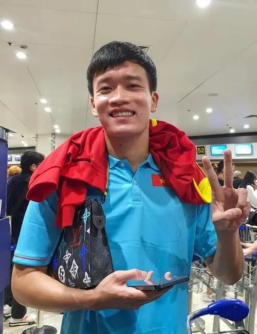 11 Hoàng Đức cầm áo khoác đỏ xanh, cười tươi trong sảnh, ánh đèn trắng và không khí sôi nổi