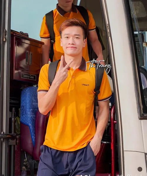 14 Hoàng Đức mặc áo vàng trên xe, đứng gần cửa, tay cầm dây, phong thái giản dị đời thường