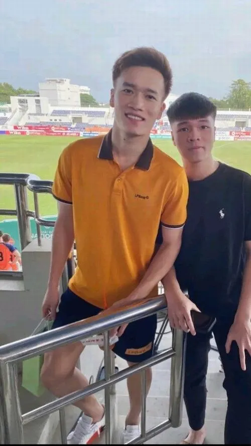 15 Hoàng Đức áo vàng dựa lan can, phía sau có bạn, ánh nắng nhẹ, cảm giác chuyến đi xa