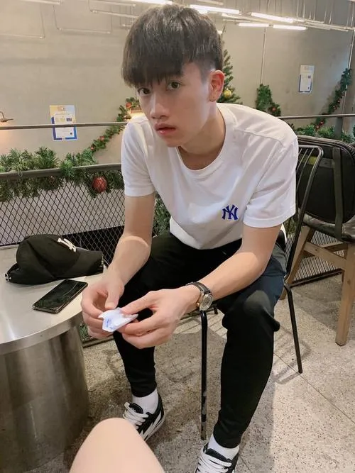 5 Hoàng Đức đời thường ngồi ghế, cầm điện thoại, chân dài, nét mặt điềm tĩnh trong phòng chờ