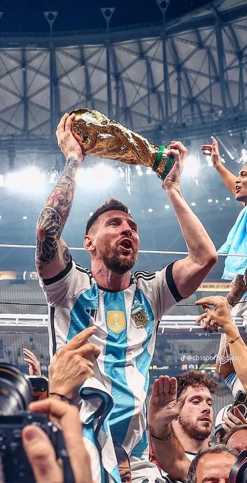 10 Ảnh bìa đẹp Messi nâng cúp trên đầu, góc rộng sân khấu, đồng đội phía dưới chụm lại.