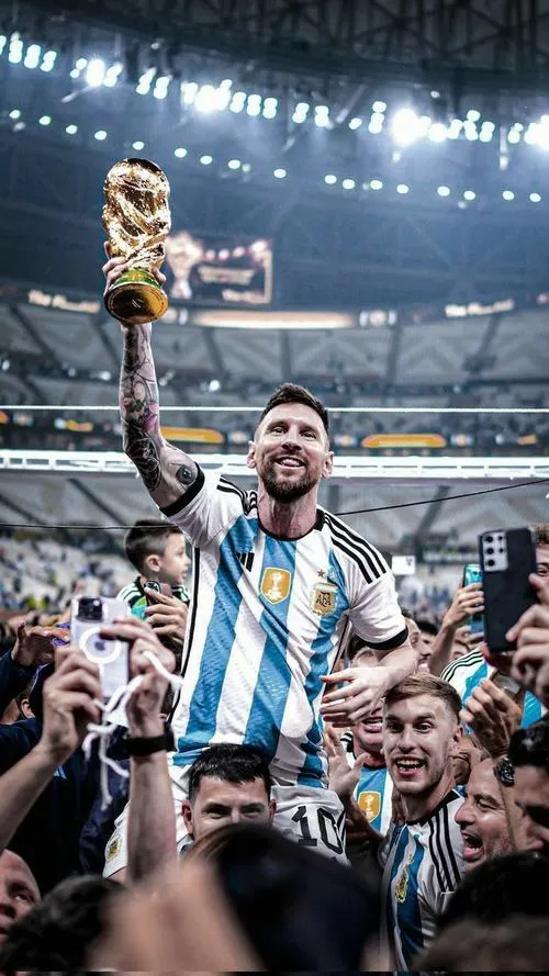 23 Tải ảnh ngầu Messi nhìn xuống cúp, viền áo đấu bắt sáng, nền khán đài mờ tạo chiều sâu.