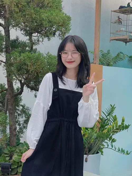 10 Bên hiên nhà bóng hồng mặc váy yếm tối màu giơ tay chào nhẹ tạo cảm giác gần gũi và gương mặt thanh tú