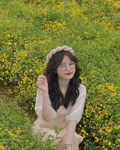 1 Giữa vườn hoa vàng gái xinh ngồi nghiêng nhẹ với gương mặt sáng và mái tóc buông dài nhìn rất hiền