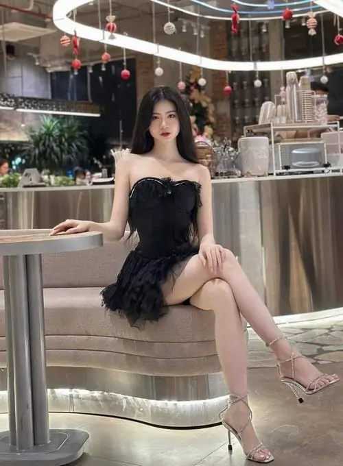 48 Ngồi trên ghế cao ở quán, cô gái diện váy đen ôm sát khoe chân dài và vòng eo gọn, bối cảnh đèn ấm làm thần thái thêm sắc nét, sexy rõ ràng nhưng vẫn giữ độ đẹp tinh tế