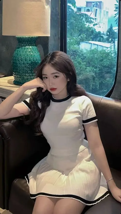 35 Khung hình mỹ nữ ghi lại cô nàng ngồi tựa ghế trong không gian thủy cung, váy sáng ôm dáng vừa đủ và mái tóc xõa mềm tạo vẻ gợi cảm kín đáo, tổng thể cute nhưng vẫn đầy sức hút