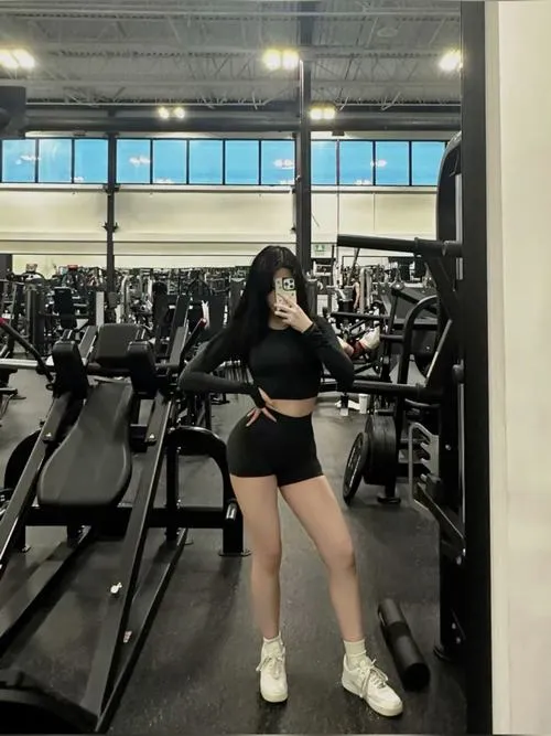 35 Cô gái quyến rũ ngồi bên dàn tạ thả lỏng sau hiệp tập làm nổi bật eo nhỏ và phong cách năng động