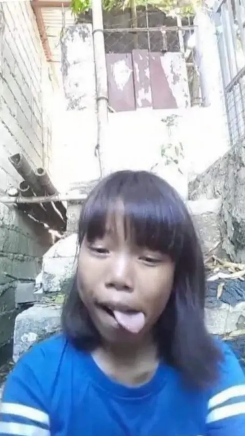 15 Ảnh nhan sắc lạ ghi lại bé gái áo xanh thè lưỡi giữa con hẻm sáng, mái tóc ngang trán và ánh mắt tinh nghịch làm gương mặt tấu hài hiện rõ, đúng kiểu ảnh chụp nhanh không canh mà lại vui ngoài mong đợi