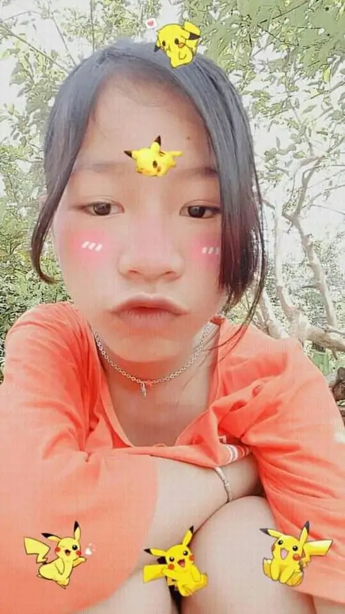 1 Ảnh gái dìm hàng với áo cam và hiệu ứng bướm vàng, cô bé chống cằm nhìn thẳng ống kính, má phúng phính và môi chu ra tạo cảm giác tấu nét rõ rệt, khung hình sáng dịu như một khoảnh khắc trêu máy ảnh rất có duyên