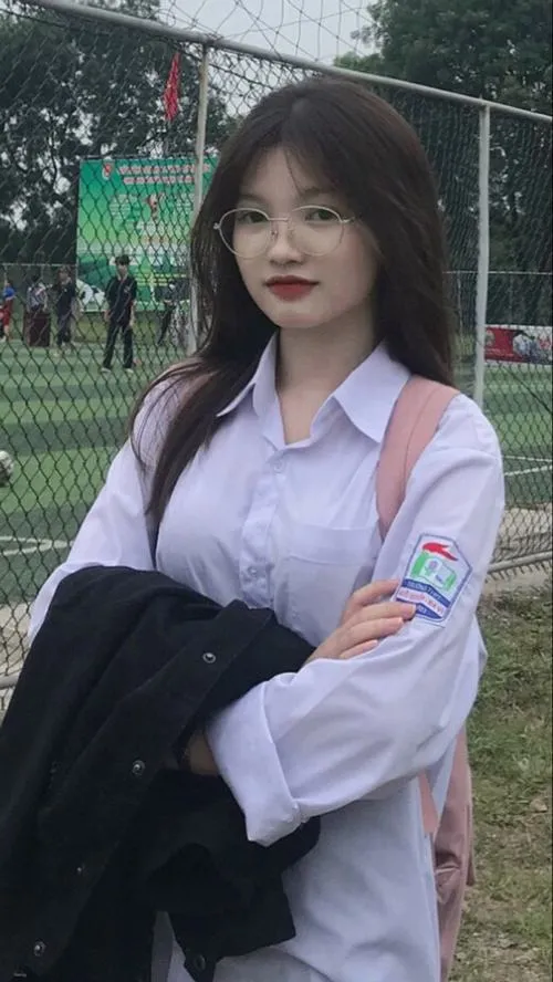 16 Nữ sinh lớp 7 cầm tập vở, biểu cảm tự nhiên khi cười dưới ánh sáng dịu nhẹ hành lang trường