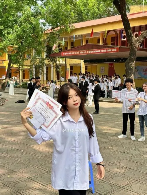 2 Nữ sinh THCS cầm cặp sách bước qua sân trường nắng nhẹ, nét ngây thơ hiện rõ trên khuôn mặt rạng ngời