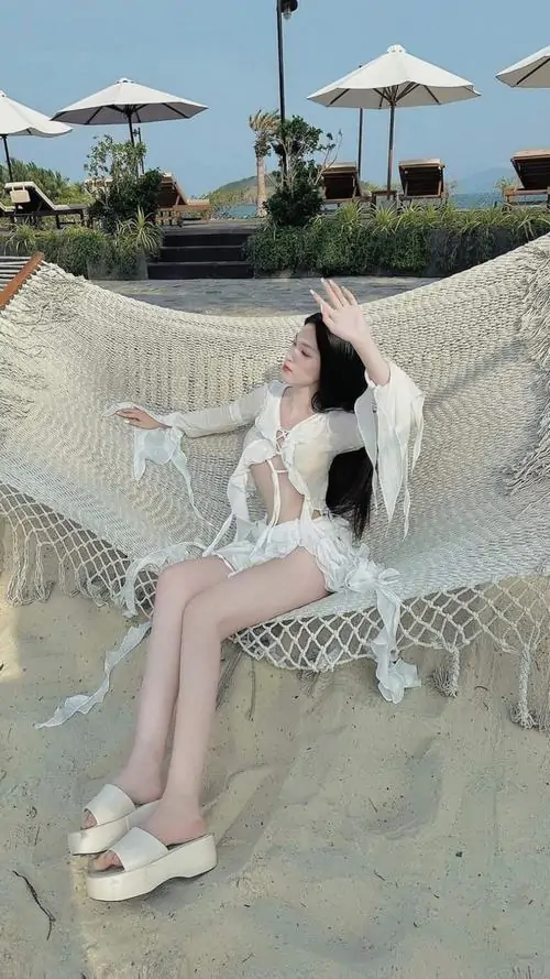 16 Ảnh gái xinh chân dài ngồi trên võng lưới gần bãi biển với váy trắng mềm và nét cuốn rất riêng