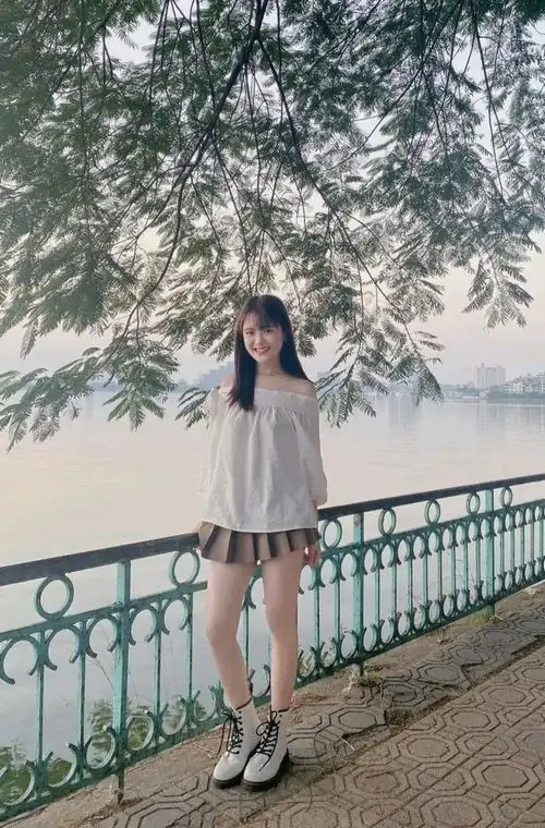 6 Hình gái đẹp chân dài mặc váy xám đứng dưới tán cây lớn cạnh lan can với cảm giác thanh thoát nhẹ nhàng