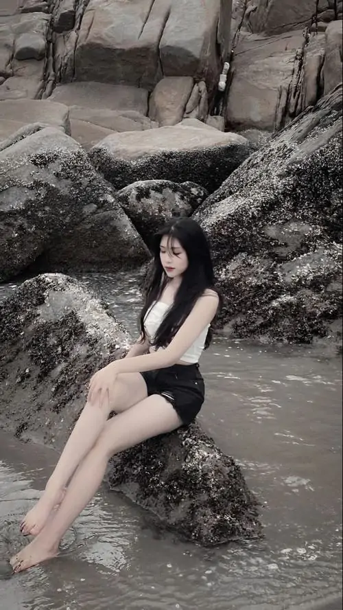 7 Ảnh hot girl eo thon ngồi trên đá giữa bãi cát tối màu với mái tóc đen dài và thần thái cuốn hút