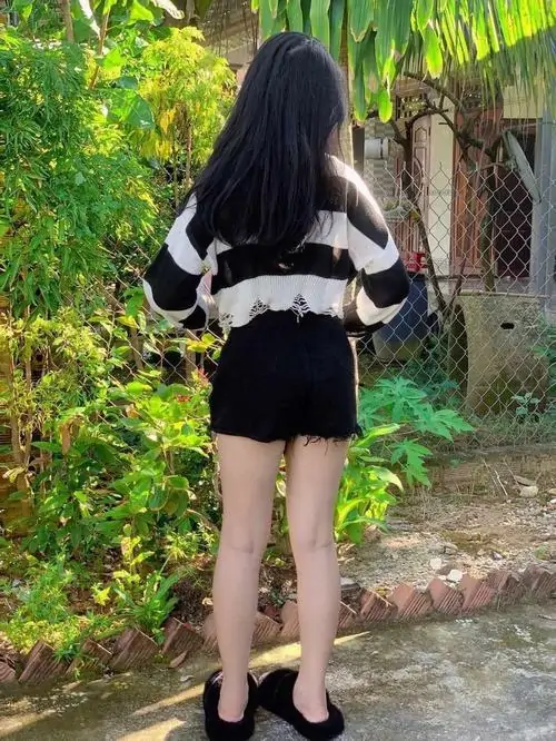 8 Ảnh gái xinh mặc quần short đen cùng áo len phối màu đứng quay lưng trong sân vườn xanh mướt