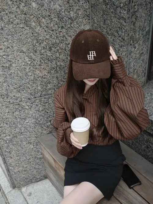 7 Hình cô gái đội mũ nâu kéo sụp khi ngồi bệt trên nền xi măng, một tay cầm cốc nước trước ngực còn tay kia tì đầu làm mặt gần như khuất hẳn, bố cục tối giản nhưng thần thái lạnh lùng vẫn hiện lên rất rõ