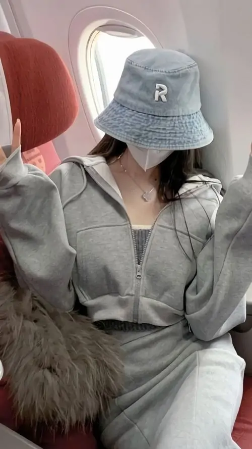 20 Trên ghế máy bay, cô gái mặc áo xám rồi kéo mũ bucket thấp xuống, đồng thời nâng điện thoại lên che nốt phần mặt còn lại, kiểu giấu gương mặt hai lớp này tạo cảm giác kín đáo, hợp ảnh nữ phong cách đường phố hiện đại