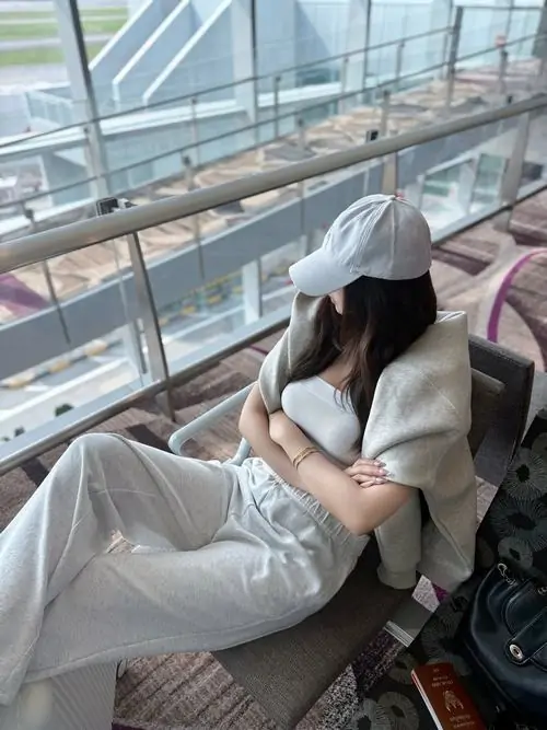 23 Hình gái đường phố ngồi tựa bên ô kính lớn, đội mũ trắng kéo thấp và xoay đầu chếch xuống để phần mặt lẫn vào vành mũ, dáng ngồi thả lỏng làm bức hình mang cảm giác thư thái, hiện đại và hơi mơ màng rất vừa