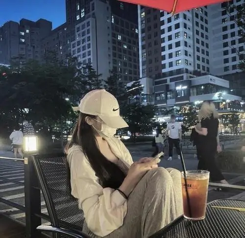 24 Trong quán nhìn ra nền phố đêm, cô gái đội mũ sáng màu rồi cúi mặt ngắm ly nước trên bàn, cách che mặt bằng vành mũ và ánh sáng thấp khiến tổng thể vừa sang vừa có nét lạnh, cực hợp mood ảnh buổi tối