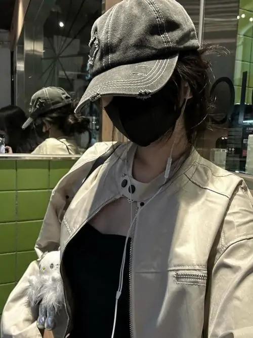 30 Ngoài sân cỏ về đêm, cô gái đội mũ tối và đeo khẩu trang đen, xoay mặt khỏi ống kính để lớp che mặt thêm kín, áo khoác be cùng nền tối giúp tổng thể lên đúng chất ngầu nhưng không lạnh và rất thời thượng