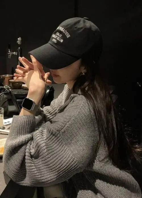 38 Trong không gian tối, cô gái đội mũ đen và đưa tay lên gần miệng khi ngồi nghiêng người, phần mặt được che bởi vành mũ lẫn bàn tay nên bức hình có độ sâu cảm xúc, hợp kiểu ảnh góc nghiêng rất thời thượng