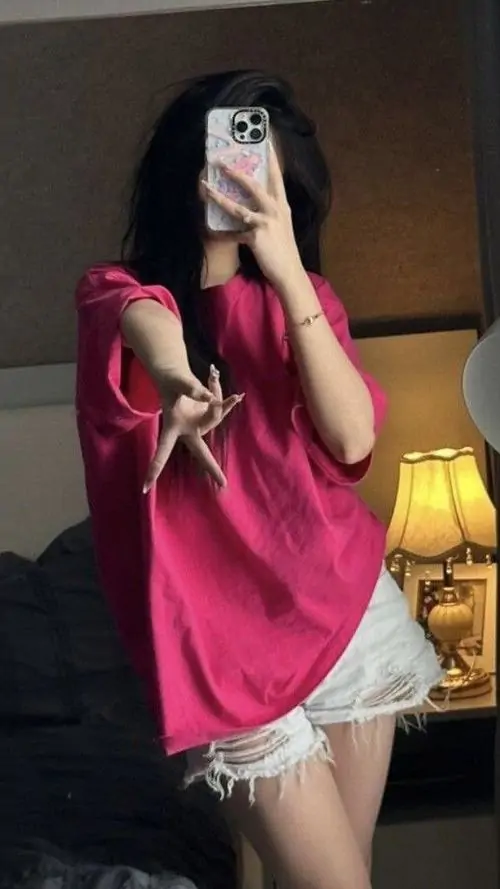 42 Trong phòng tối, cô gái mặc váy hồng rộng và đứng trước gương, lấy điện thoại che kín gương mặt trong lúc chân bước nhẹ sang bên, dáng chụp đơn giản nhưng tổng thể vẫn nổi bật nhờ vẻ trẻ, hiện đại và có gu