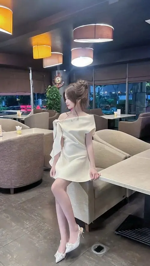 14 Giữa quán cà phê hiện đại, nàng bước nhẹ trong váy trắng ngắn, gót chân và bắp chân lên hình thanh thoát nhờ ánh đèn ấm, tổng thể sang mà không gồng, nhìn rất hợp kiểu ảnh nữ xinh pose dáng