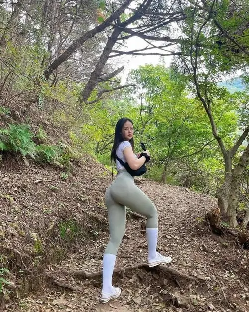 1 Giữa triền dốc phủ lá khô, cô gái đứng nghiêng dưới tán cây thưa với áo tối ôm người và quần sáng gọn chân, góc chụp thoáng giúp vóc dáng thanh hơn, nhìn đẹp theo kiểu tự nhiên rất dễ ngắm