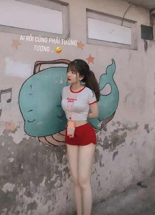 38 Trước bức tường vẽ ngoài trời, nàng mặc áo đỏ nổi trên nền cũ và đứng gọn trong quần ngắn sáng, cơ thể nhỏ nhắn lên hình khá xinh, cảm giác cute cùng tinh nghịch làm bức ảnh rất có sức sống