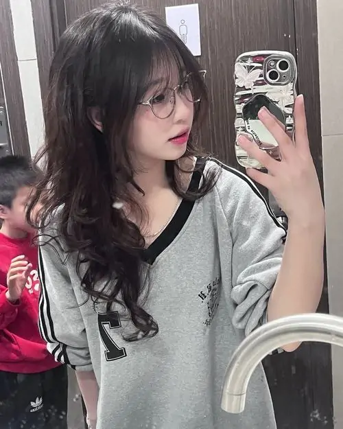 25 Ảnh gương ghi lại cô gái đeo kính trong áo xám rộng mang vẻ gần gũi với mái tóc xoăn buông nhẹ