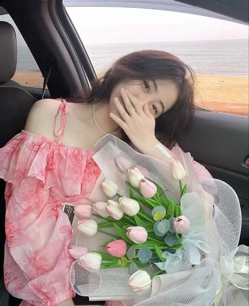 27 Trong xe chiều muộn cô gái ôm hoa tulip mang gam màu tươi sáng với váy hồng trễ vai và tóc buông